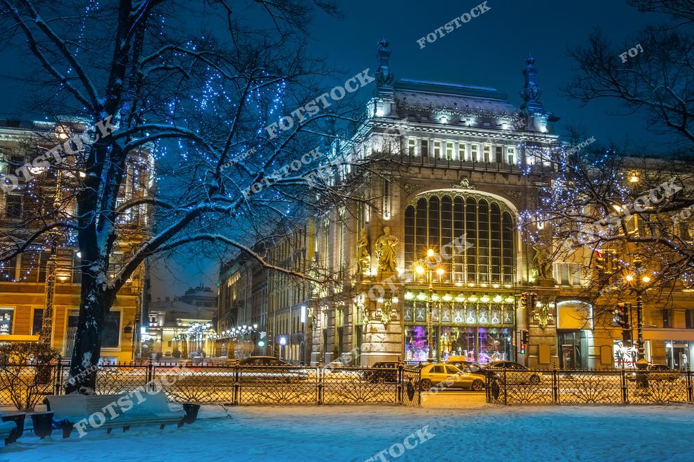 На фотографии изображен зимний вечер на Невском проспекте в Санкт-Петербурге, одном из самых известных и оживленных улиц города. Елисеевский магазин, с его великолепной архитектурой и новогодней иллюминацией, привлекает внимание своей красотой. Снежное покрытие и вечернее освещение создают атмосферу зимнего путешествия по одному из самых красивых городов России.